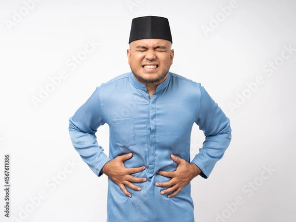 Obraz Asian muslim man had a stomach ache and gastritis. Islamic man put hand on his stomach and squeezed it to relax and soothe has go to toilet need to poop. Shot on isolated white background.