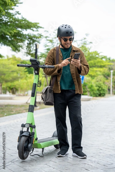 Obraz Young Asian man rent the scooter EV scan by smartphone. Sustainable save energy lifestyle. Commute and carbon neutral transportation. Asian tourist man put on helmet ride the scooter EV