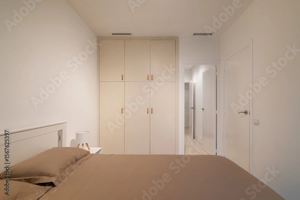 Obraz Minimalist bedroom view with taupe bedding, white built-in wardrobe and clean neutral walls