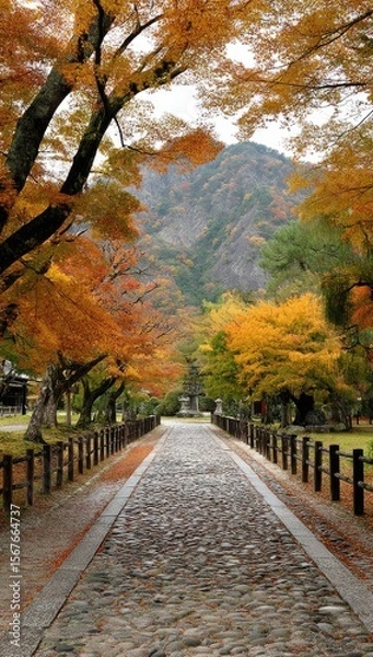 Obraz Autumnal pathway lined with vibrant fall foliage, leading into a misty mountain range