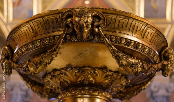 Fototapeta Close-up of an ornate bronze or brass basin with a sculpted ram's head and classical decorative motifs.