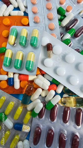 Fototapeta Various capsules and tablets scattered on a surface represent medications and pharmaceutical products for health concept