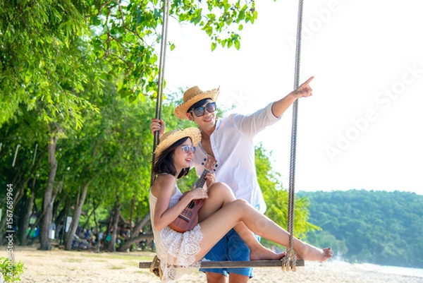 Fototapeta Romantic lifestyle asian couples lover playing an ukulele on the hammock. relax and honeymoon in luxury resort near the beach. Thailand. Summer,Travel, Valentine Concept.