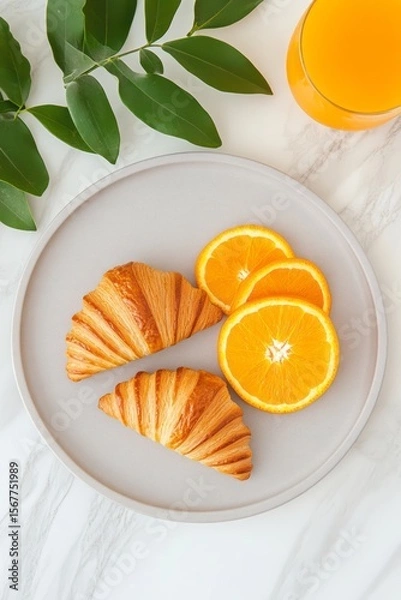 Fototapeta Elegant breakfast flat lay with croissants, orange slices, and fresh juice on marble table, bright orange and yellow tones, aesthetic composition with green sprig
