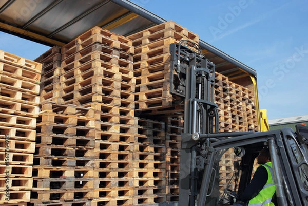 Obraz Counterbalance driver unloading empty euro pallets for local warehouse.
