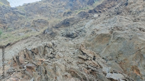 Fototapeta Rocky Mountainside, Dry Grass, Grey and Brown Tones, Rugged Texture, Natural Landscape, High-Angle View,  Geological Formation,  Erosion,  Arid Climate.