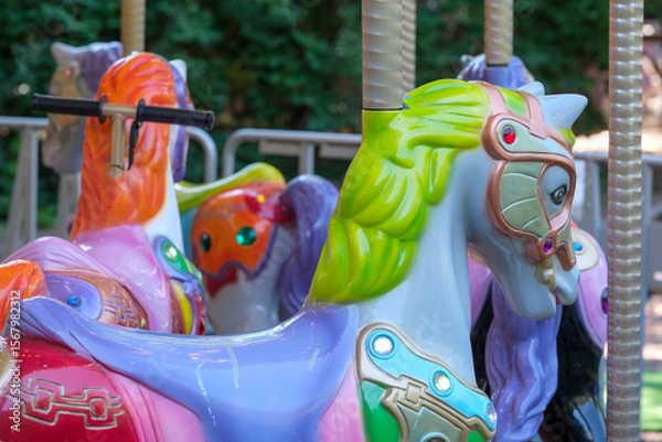 Fototapeta Colorful carousel horses waiting for joyful riders at the park