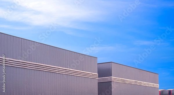 Fototapeta Row of factory warehouse industrial buildings with ventilation louver on gray aluminium corrugated metal wall against blue sky background, Perspective side view with copy space