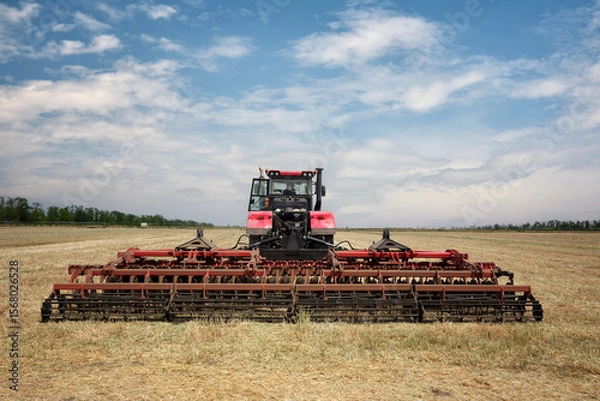 Fototapeta Rear view of a large tractor with a plow standing in a field. Start tillage after harvest.