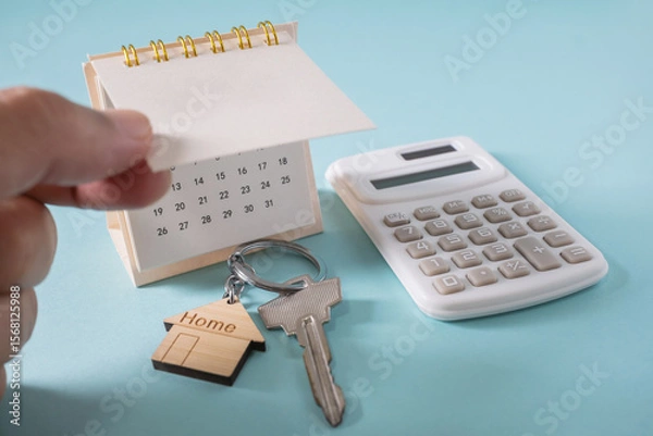 Fototapeta Home loan interest payment appointment. Hands opening calendar, house keys, calculator on the white table.