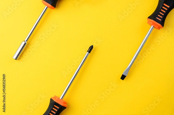 Fototapeta Three screwdrivers partially visible on yellow background with empty space, minimal tool layout