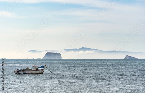 Fototapeta A tranquil scene with a fishing boat floating in the calm waters of Pacific Ocean at Paracas National Reserve, Peru.