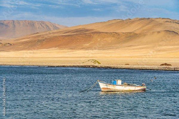 Fototapeta A tranquil scene with a fishing boat floating in the calm waters of Pacific Ocean at Paracas National Reserve, Peru.