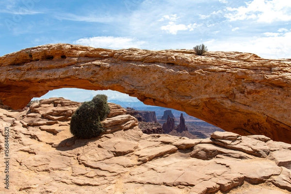 Fototapeta The pothole Mesa Arch (or Rotary Arch and Trail Arch) on the Island in the Sky mesa in Canyonlands National Park, Utah, with views of canyons and the La Sal Mountains in the distance