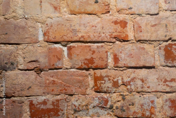 Fototapeta Close-up of an old red brick wall with weathered, textured surfaces and visible mortar joints. 