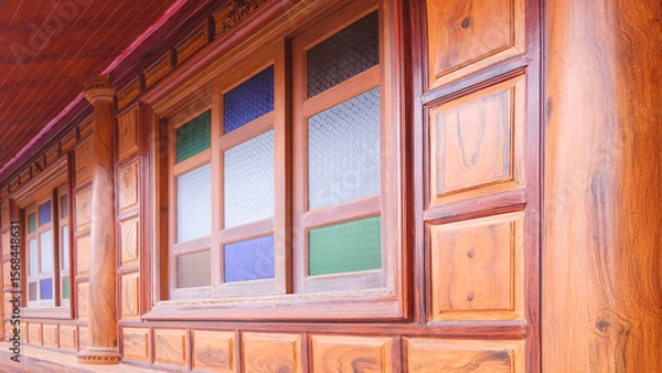 Fototapeta Wooden house in vintage retro style with multicolored stained glass window on teak wood wall background, perspective side view