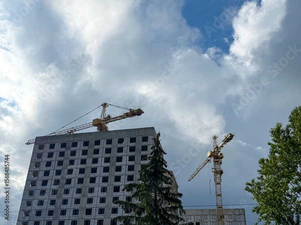 Obraz Crane and building construction. construction site. Multi Storey Residential Buildings construction. Tower crane on formworks. Construction crane on Housing. Building site with cranes against sky. 