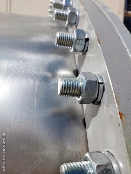 Obraz Detailed Close-Up of Flange With Bolts and Nuts in Industrial Setting Under Bright Sunlight
