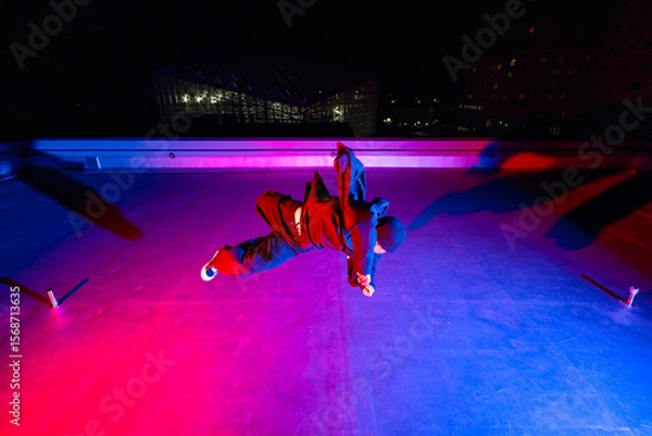 Obraz ビル屋上でアクロバティックなポーズを決めるダンサーの若者