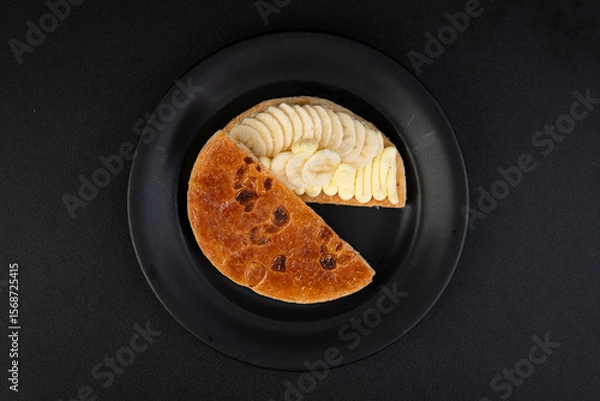 Fototapeta Banana tart on a black plate, top view