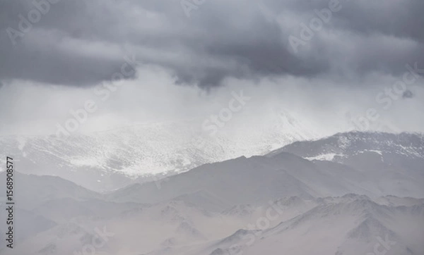Fototapeta Panorama of mountain peaks with snow and glaciers, a landscape in the highlands of the Tien Shan in Pamir in cloudy weather with clouds and rain, high-mountain steppe and mountains in the background
