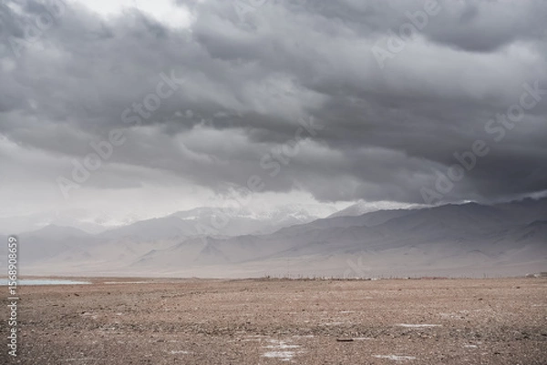 Fototapeta Panorama of mountain peaks with snow and glaciers, a landscape in the highlands of the Tien Shan in Pamir in cloudy weather with clouds and rain, high-mountain steppe and mountains in the background