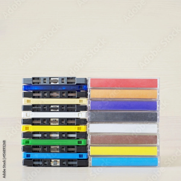 Fototapeta Stack of old colorful dirty audio cassettes and cases on the brown wooden shelf