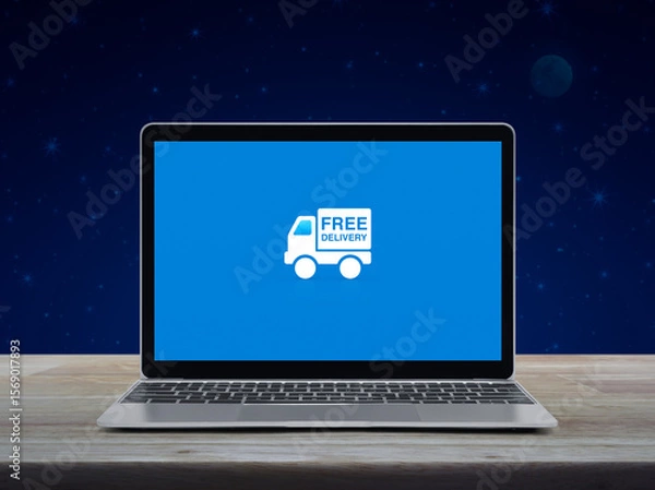 Fototapeta Free delivery truck flat icon on modern laptop computer screen on wooden table over fantasy night sky and moon, Business transportation online concept
