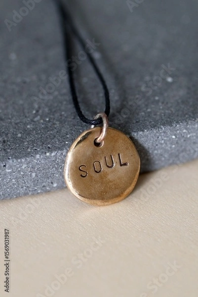 Fototapeta Bronze Handcraft Soulful Amulet Pendant with Inspirational Word on Gray Stone Surface.
