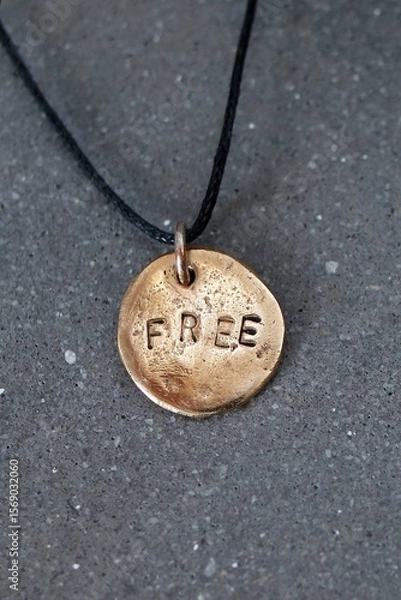 Fototapeta Bronze Freedom Pendant on Black Cord, Symbolizing Independence, Aspiration, and Self-Expression.