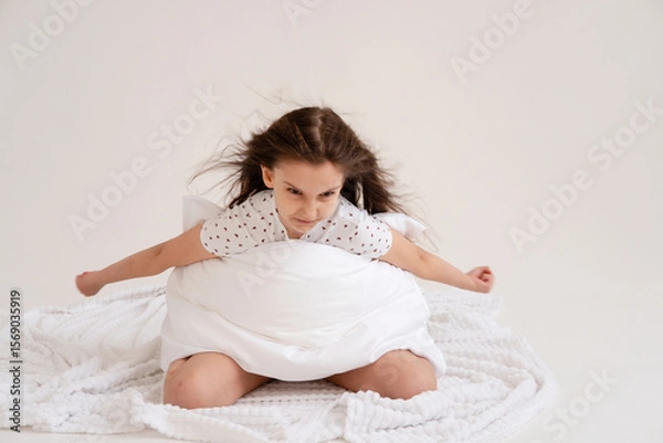 Obraz Portrait of cheerful positive relaxing girl getting ready for bed hugging pillow on white background. Good morning concept. Good sleep and healthy lifestyle.