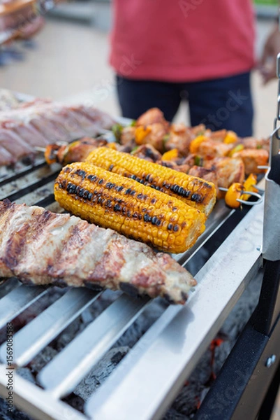 Fototapeta Chef grilling corn on the cob, ribs and kebabs for a summer barbecue