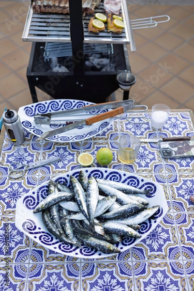 Fototapeta Fresh sardines ready for grilling on a decorated table with lemon and lime