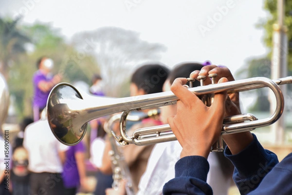 Fototapeta A student plays the trumpet in a school marching band during outdoor practice, focusing on teamwork, discipline, and musical performance.