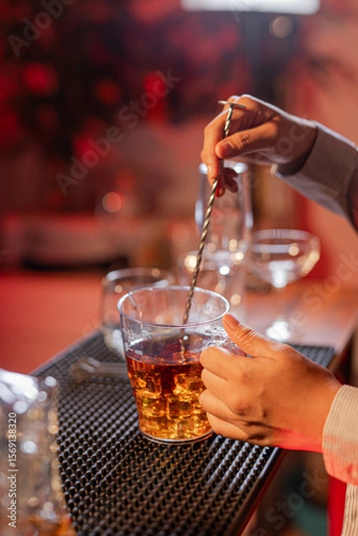 Fototapeta Professional female bartender preparing alcoholic drinks in a bar