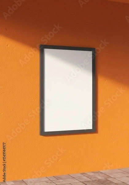 Fototapeta Photo of a blank framed poster hangs on an orange textured wall with sunlight