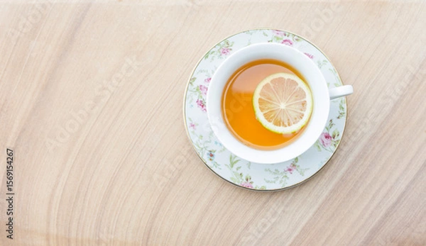 Obraz Hot tea with lemon slice in flower tea cup on sand stone background, hot drink, healthy drink