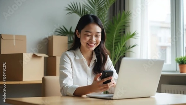 Obraz cheerful woman running an online business from home, using her phone and laptop