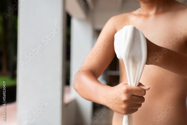 Fototapeta Close-up of a young Muay Thai fighter wrapping his hand with traditional cloth. The image captures detail and texture, highlighting strength, focus, and cultural authenticity.
