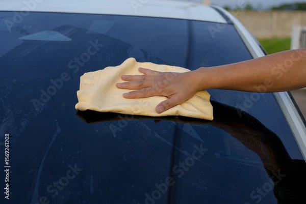 Fototapeta A smiling man is washing his car with soapy water under bright sunlight, showing his enthusiasm and joy in his daily work.