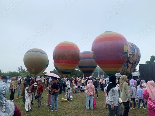 Fototapeta Colorful hot air balloons festival display distinct horizontal stripes are being inflated on the cloudy sky provide  backdrop. 