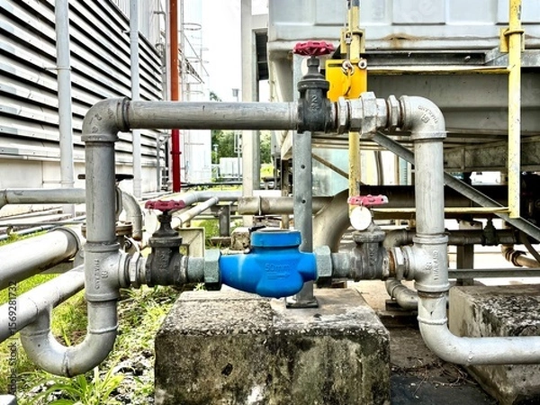 Obraz pipes and valves, Close-up of stainless steel industrial piping system with valves and control components in a factory. Used in fluid transfer, process engineering, and manufacturing environments.