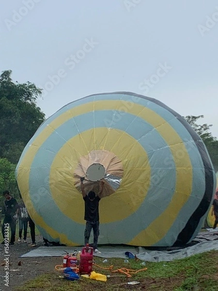 Fototapeta Colorful hot air balloons festival display distinct horizontal stripes are being inflated on the cloudy sky provide  backdrop. 