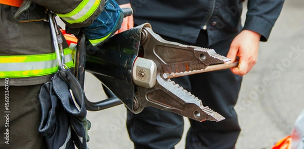 Fototapeta Firefighter uses hydraulic tool to rescue trapped individual during emergency response in urban area