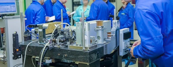 Fototapeta Engineers collaborate on machine assembly in a modern workshop during a training session