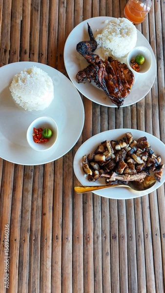 Fototapeta Grilled chicken inasal and pork liempo paired with rice served on a bamboo table, authentic traditional local Filipino meal in the Philippines