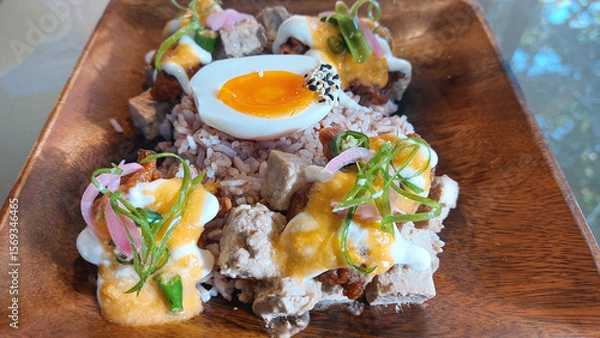 Fototapeta Close up to a garnished and visually pleasing wooden plate of steamed rice, egg, fried tofu cubes and fried oyster mushroom showing a healthy vegetarian meal for health and wellness