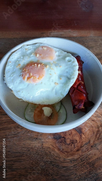 Fototapeta Overhead view of a bowl of sunny-side-up eggs, rice, and hot dog which is a typical local Filipino breakfast meal and comfort food