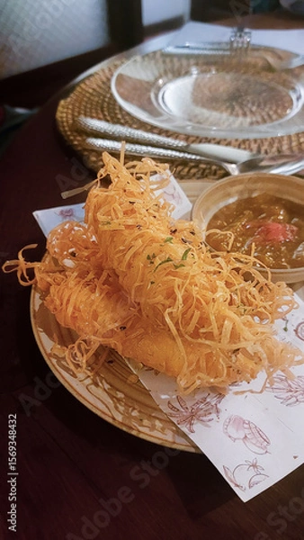 Fototapeta A fancy appetizer of crispy deep-fried mozzarella covered in shredded lumpia wrapper, served with a side dukkha and mango chutney. A fusion of Filipino and Middle Eastern cuisine