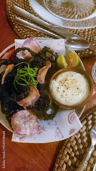 Fototapeta Fried inky squid or pusit ring and sweet purple yam chips served with calamansi aioli, a fancy twist to a local traditional Filipino cuisine in a restaurant